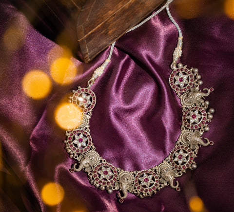 Intricate elephant heads alternate with radiant star patterns, embellished with rubies and sparkling white stones