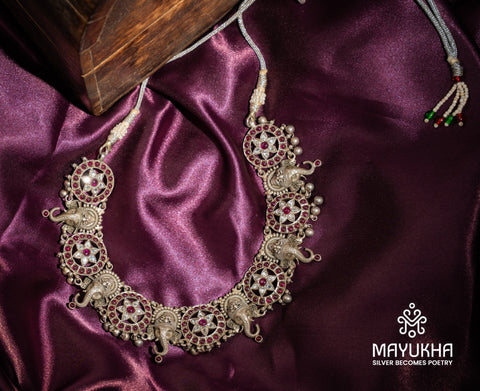 Intricate elephant heads alternate with radiant star patterns, embellished with rubies and sparkling white stones